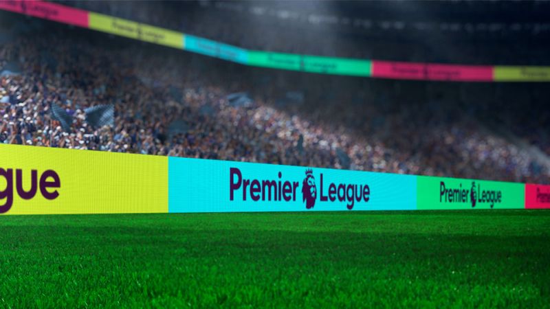 Premier League LED perimeter boards glowing above the pitch in a packed stadium at night